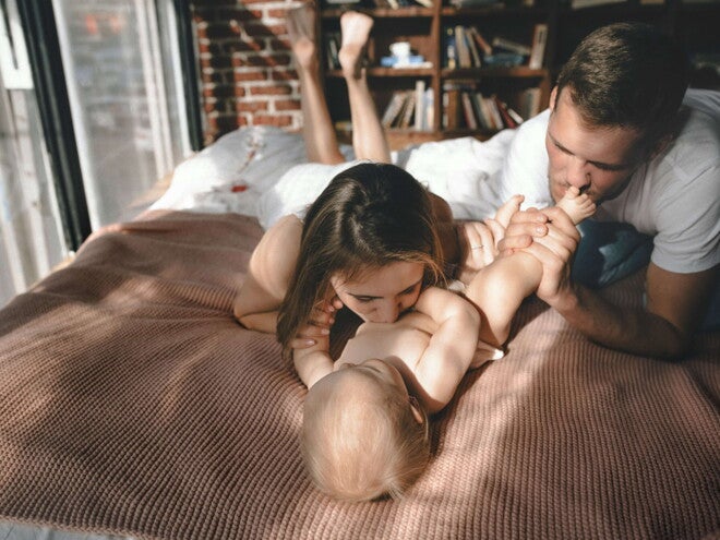 foreldre og baby på sengen foreldre og baby på sengen